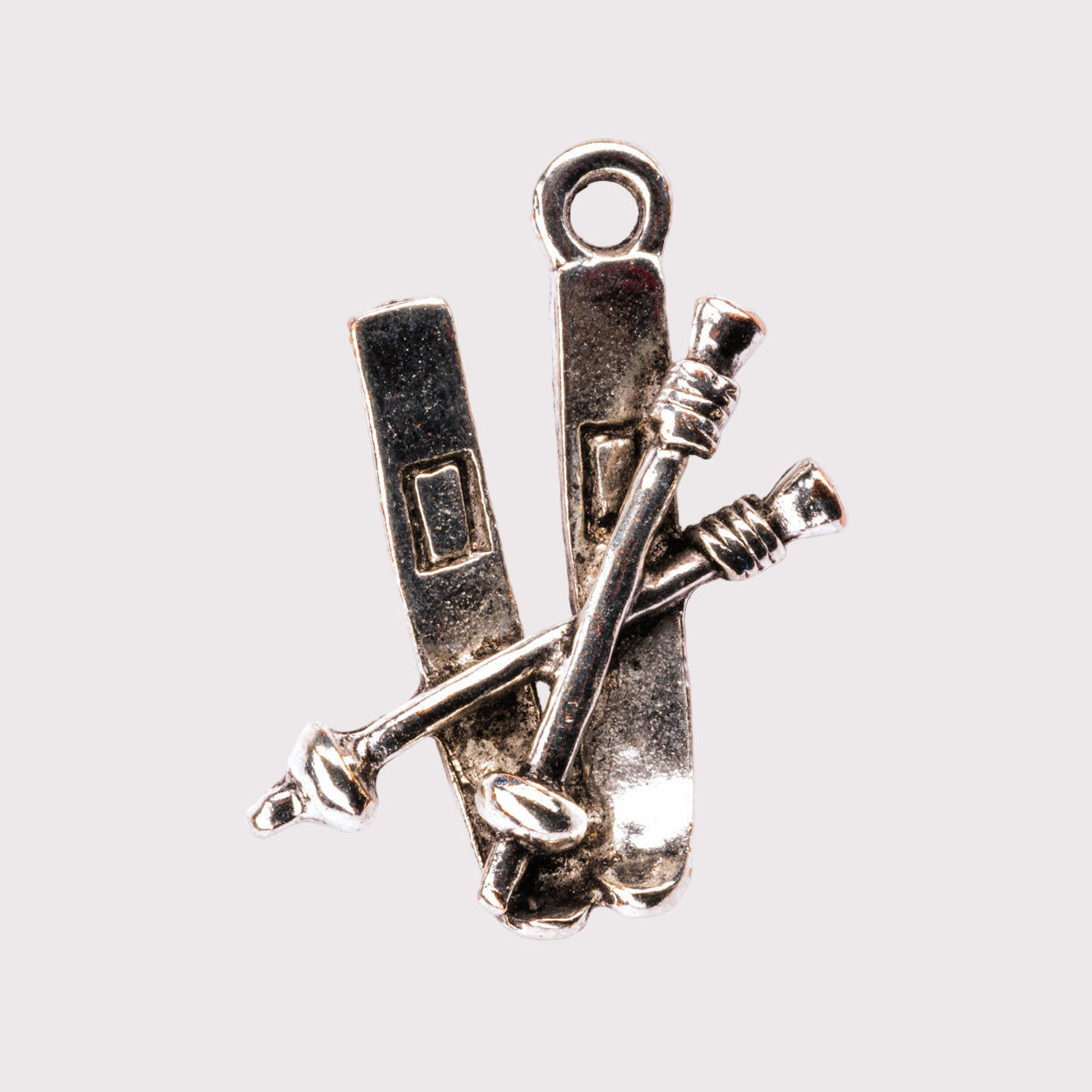 A silver charm featuring skis with ski poles crossed over them.