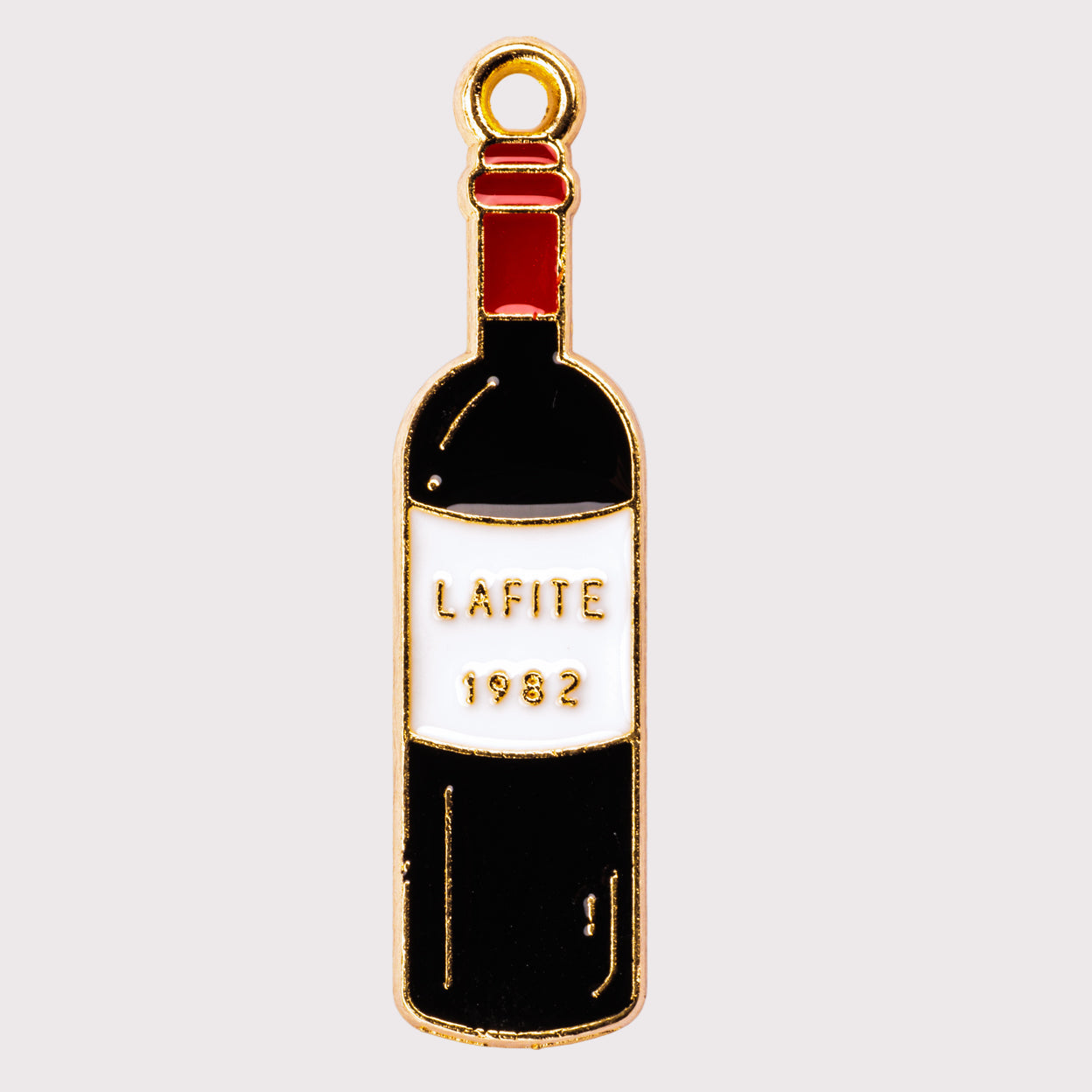 A gold-colored wine bottle charm with 'LAFITE 1982' printed on it.
