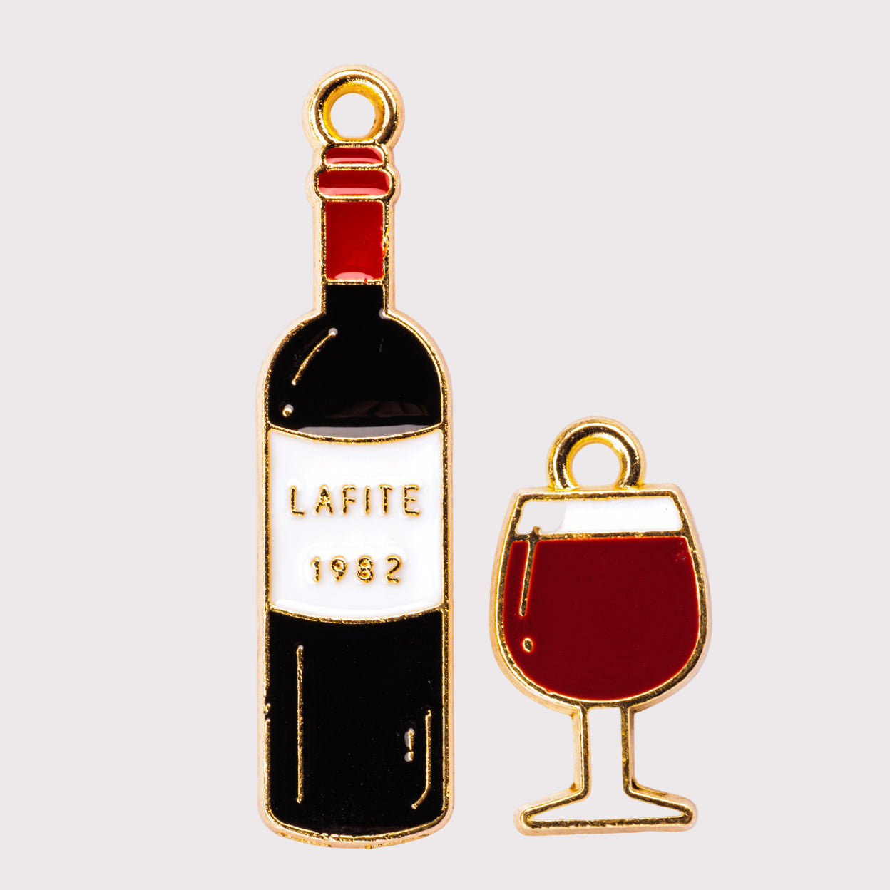 Two charms, one in the shape of a wine bottle with the label Lafite 1982, and the other in the shape of a wine glass filled with red liquid.