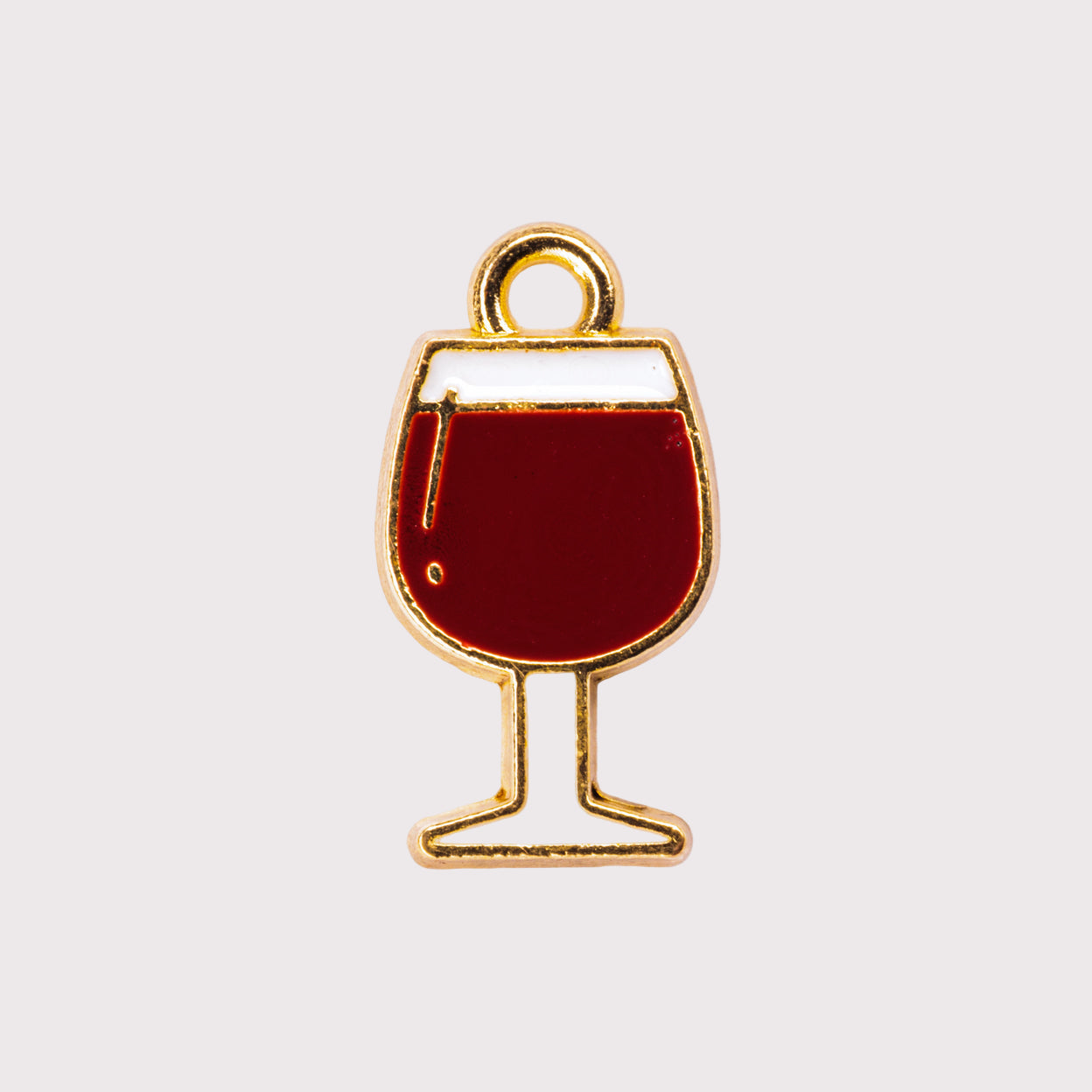 A gold-colored metal charm shaped like a wine glass filled with red liquid.