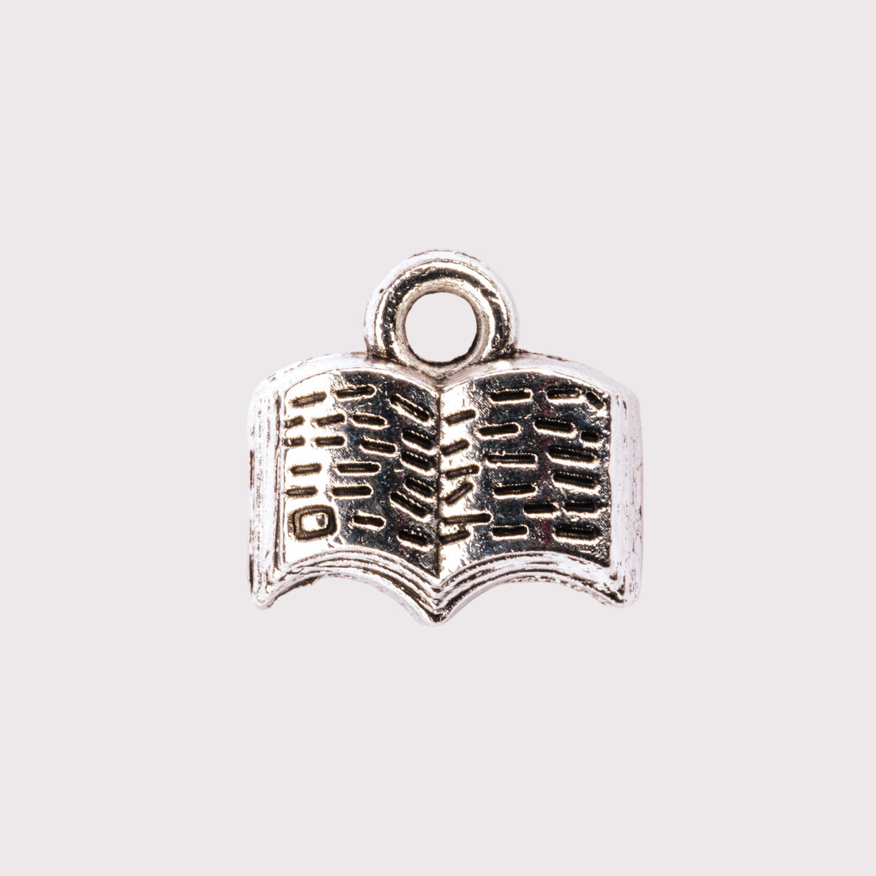 A silver charm in the shape of an open book.